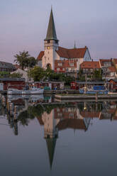 Dänemark, Bornholm, Ronne, St.-Nikolaus-Kirche, die sich in der Abenddämmerung im Küstenwasser spiegelt - KEBF02765