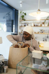 Barista verpackt Essen in Papiertüte in einem Coffeeshop - EBSF03981