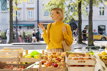 Lächelnde Frau kauft Äpfel auf dem Bauernmarkt - NDEF01297