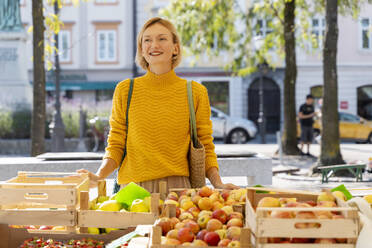 Nachdenkliche Frau in der Nähe von Obstkisten auf dem Bauernmarkt - NDEF01299