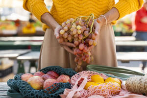 Frau hält eine Traube frischer Weintrauben auf dem Bauernmarkt - NDEF01302