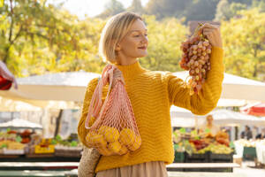 Lächelnde Frau mit frischen Früchten auf dem Bauernmarkt - NDEF01306