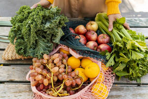 Mesh bags with fresh fruits and vegetables on table at farmer's market - NDEF01309