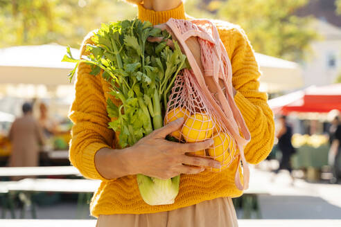 Frau mit Sellerie und Netzbeutel mit Mandarinen auf dem Bauernmarkt - NDEF01316