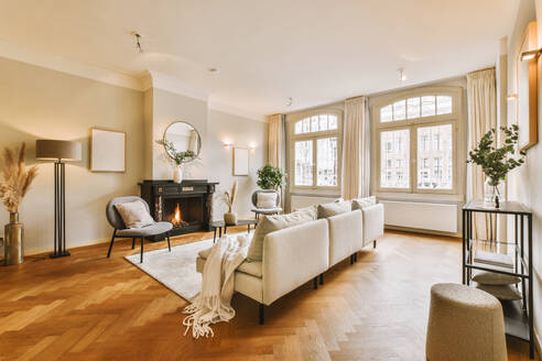 Interior of living room with comfortable couch placed in front of fireplace with windows in contemporary house - ADSF48753