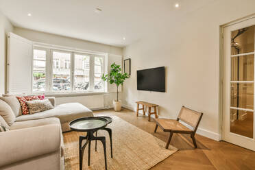 Sofa and coffee tables placed in front of television by large window in spacious living room in modern apartment - ADSF48778