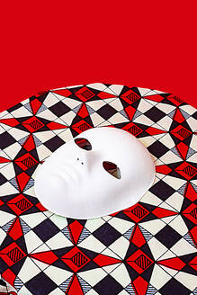 Hohe Winkel der weißen Maske auf dem Tisch gegen roten Hintergrund platziert - ADSF48789