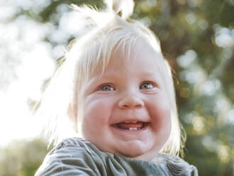 Lächelndes kleines Mädchen mit blondem Haar im Park - NLAF00154