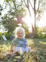 Cute Baby Mädchen im Pferdeschwanz sitzen auf Gras im Park - NLAF00155