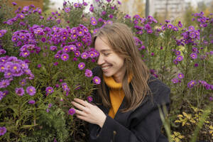 Glückliche Frau in der Nähe von Aster Blumen im Park - LESF00499