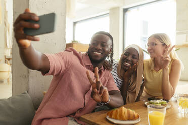 Smiling man taking selfie with friends at coffee shop - EBSF04005