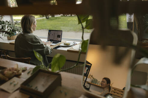 Freiberufler bei der Arbeit mit Laptop und Spiegelbild des Besitzers in einem Café - VIVF01136