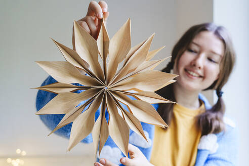 Smiling girl holding star shaped Christmas decoration - IHF01783