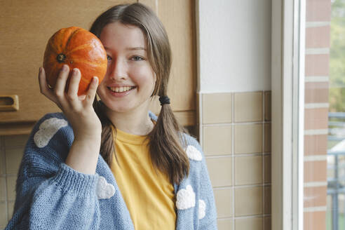 Glückliches Mädchen mit Kürbis in der Hand zu Hause - IHF01796