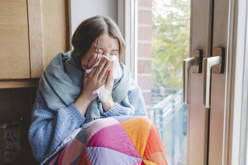 Krankes Mädchen putzt sich die Nase mit einem Taschentuch in der Nähe des Fensters zu Hause - IHF01816