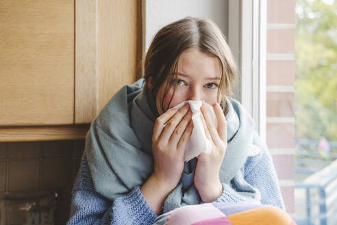 Teenager-Mädchen schnäuzt sich zu Hause auf einem Taschentuch - IHF01817