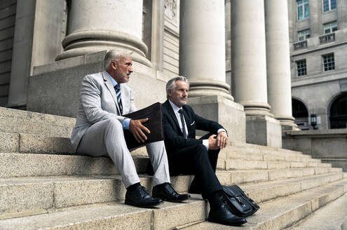 Ältere Geschäftsleute sitzen auf einer Treppe zusammen - OIPF03604