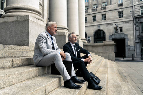 Nachdenklicher Geschäftsmann sitzt mit einem Kollegen auf einer Treppe - OIPF03607