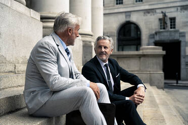 Smiling businessman having discussion with colleague on steps - OIPF03608