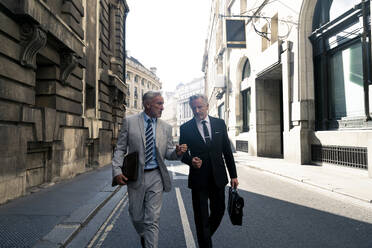 Businessmen walking and having discussion together on road - OIPF03616