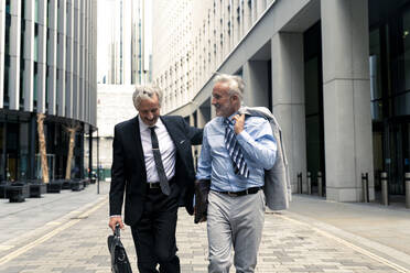 Smiling senior businessmen walking and talking with each other - OIPF03635