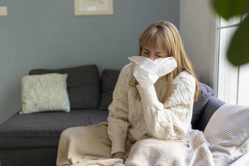 Kranke Frau schnäuzt sich zu Hause die Nase mit Seidenpapier - SVKF01690