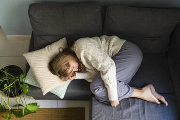 Frau mit Bauchschmerzen schläft auf dem Sofa zu Hause - SVKF01694