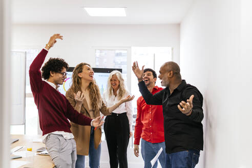 Happy multiracial business colleagues dancing together in office - PBTF00373