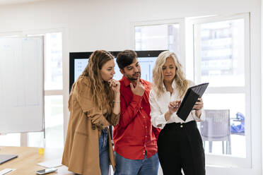 Businesswoman with tablet PC planning strategy with colleagues at work place - PBTF00375