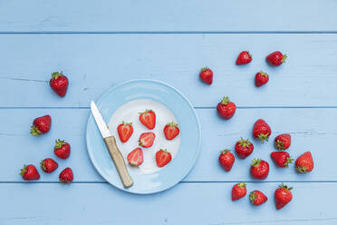 Teller, Küchenmesser und reife Erdbeeren auf blauer Holzoberfläche - GWF07931