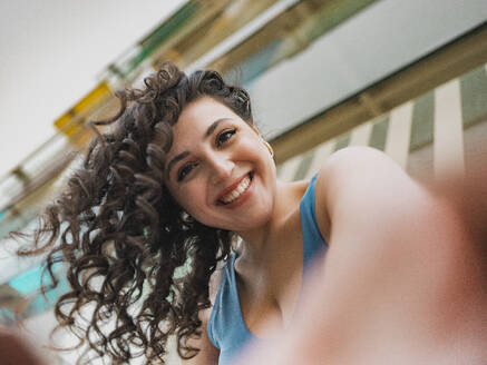 Beautiful woman with curly hair taking selfie - MFF09408