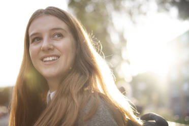 Glückliche junge Frau mit langen Haaren im Sonnenlicht - AMWF01955