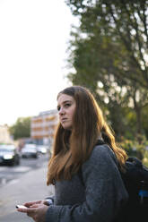 Thoughtful young woman with backpack standing on street - AMWF01956