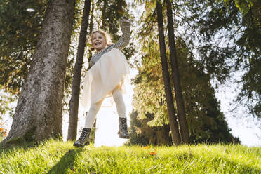 Cheerful girl jumping near trees in forest - NDEF01334