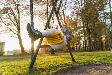 Girl swinging on swing at playground in park - NDEF01366