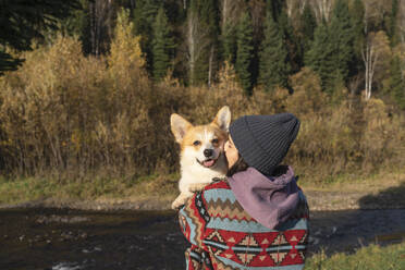 Junge Frau umarmt am Wochenende im Park einen Pembroke Welsh Corgi - VBUF00477