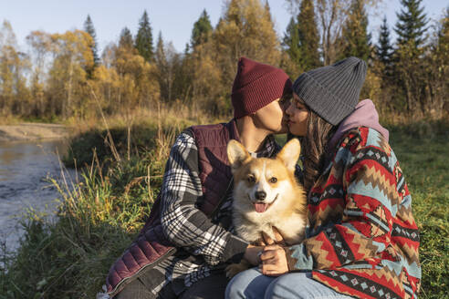 Mann küsst Frau mit Hund in öffentlichem Park am Wochenende - VBUF00481