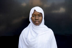 Ernste junge Frau mit Hidschab vor einer schwarzen Wand - DLTSF03673