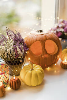 Halloween-Dekoration mit Lichtern und geschnitzten Kürbissen auf der Fensterbank - ONAF00657