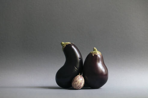 Eggplants and single gooseberry against gray background - JUBF00444