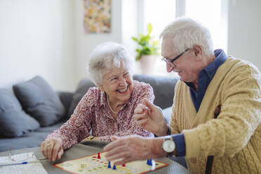 Glückliches älteres Paar, das zu Hause das Brettspiel Ludo spielt - HAPF03224