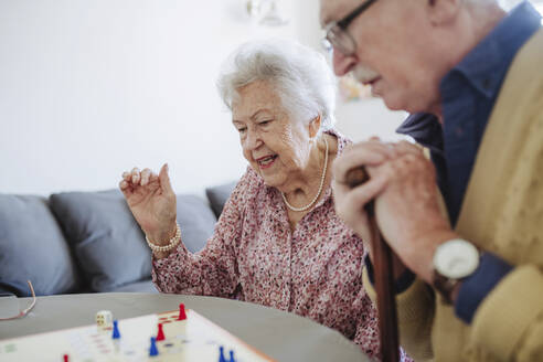 Ältere Frau spielt Ludo mit Mann am Tisch - HAPF03231