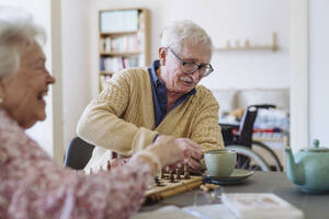 Glückliche ältere Frau mit Mann, der eine Teetasse am Tisch hält - HAPF03244