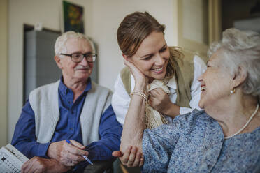 Cheerful senior woman embracing healthcare worker at home - HAPF03273