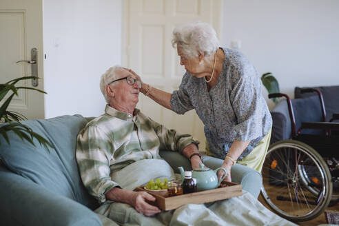 Senior woman consoling man sitting with tray at home - HAPF03306