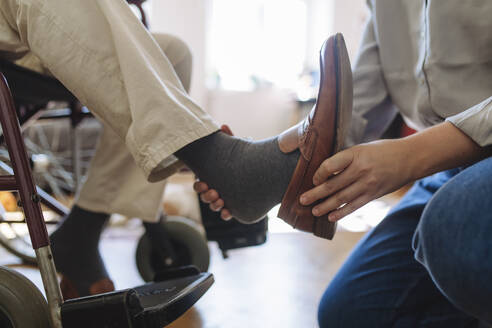 Healthcare worker removing man's shoe at home - HAPF03316