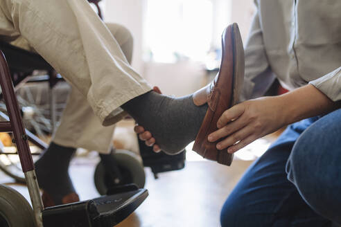 Mitarbeiter des Gesundheitswesens entfernt den Schuh eines Mannes zu Hause - HAPF03316