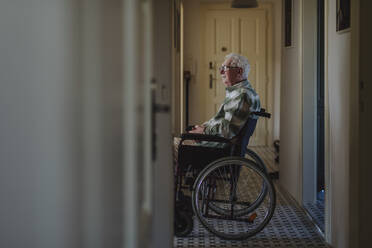 Contemplative senior man sitting in wheelchair at home - HAPF03320