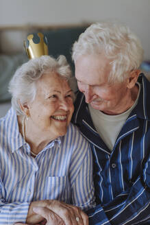 Glückliche ältere Frau mit Krone und Blick auf einen Mann - HAPF03363
