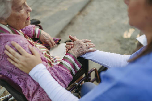 Healthcare worker holding hands and consoling senior woman - HAPF03389